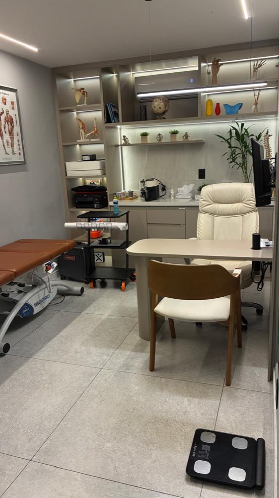 Sala de consulta com maca, mesa médica e armários iluminados
